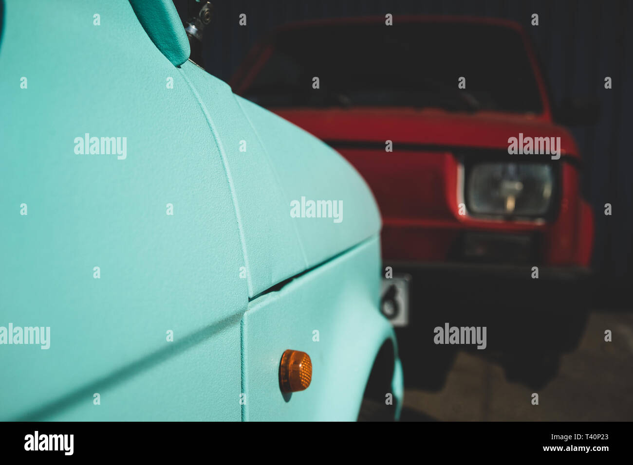 A light green car with an orange lantern opposite a red car with