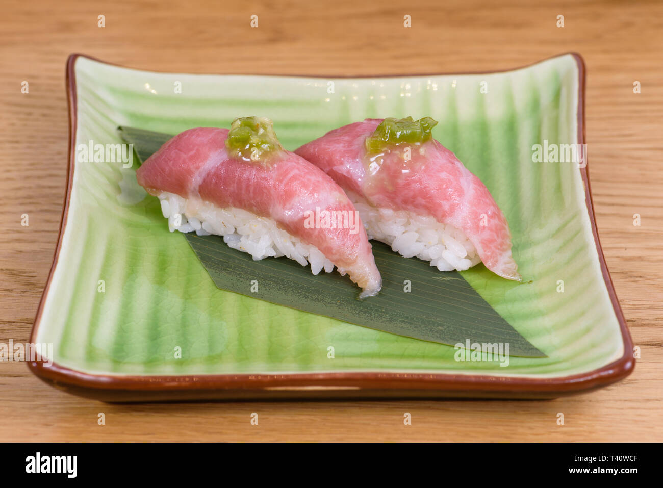 nigiri of raw beef Kobe beef with green sauce, wooden table background Stock Photo