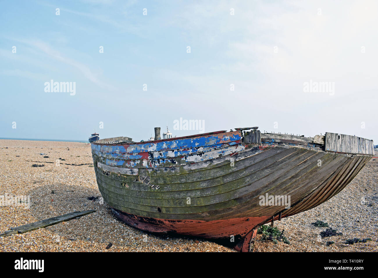 A close up of an abandoned old fishing boat on the pebble beach at ...