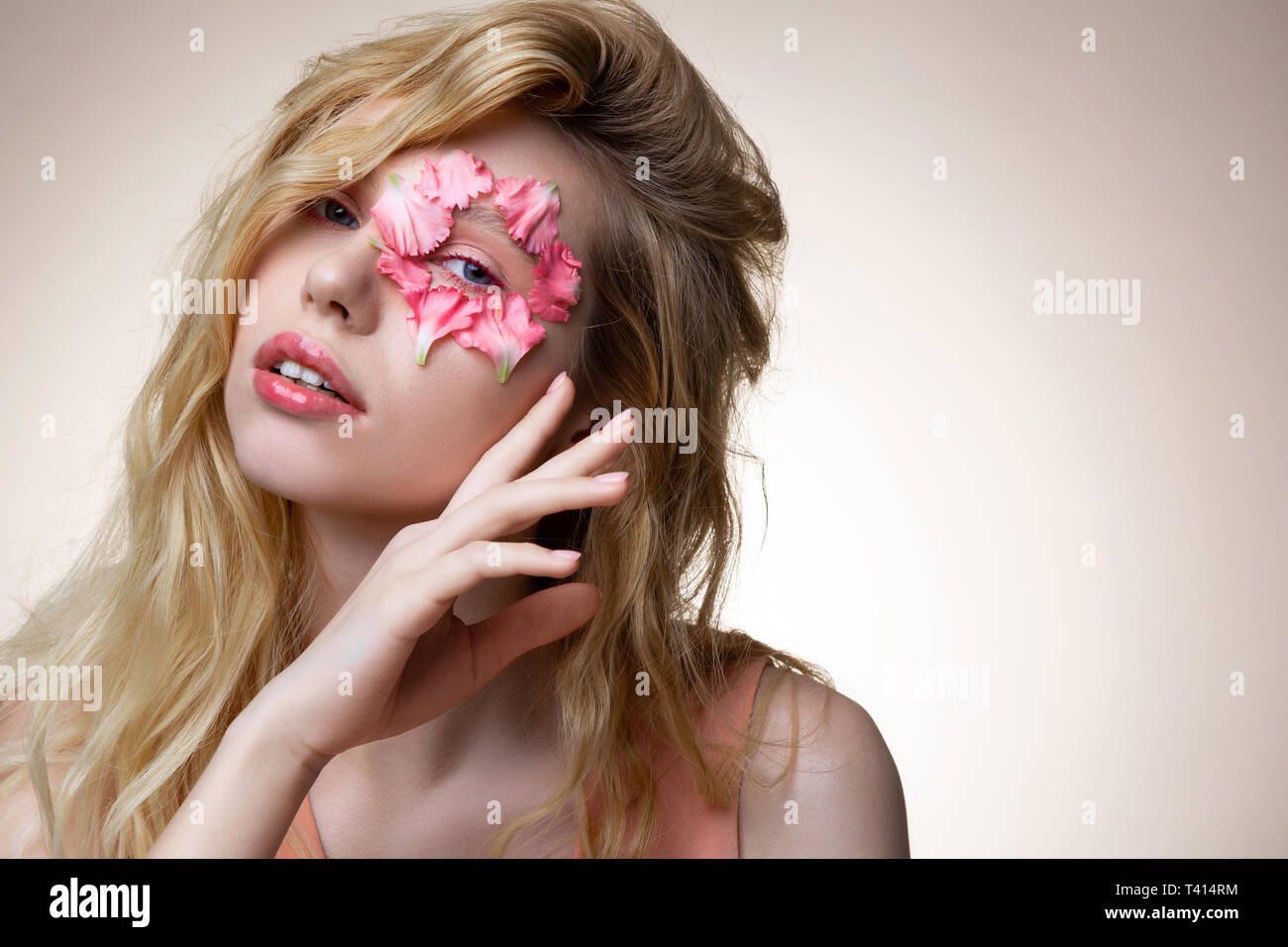 Model with pink lip gloss posing with pink petals on face Stock Photo ...