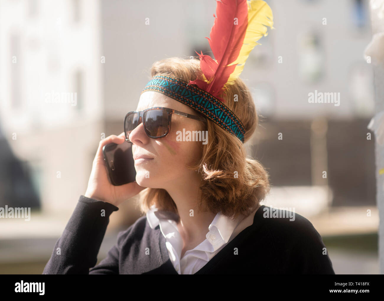 Woman dressed up in North American tribal costume talking on her mobile phone, Germany Stock Photo