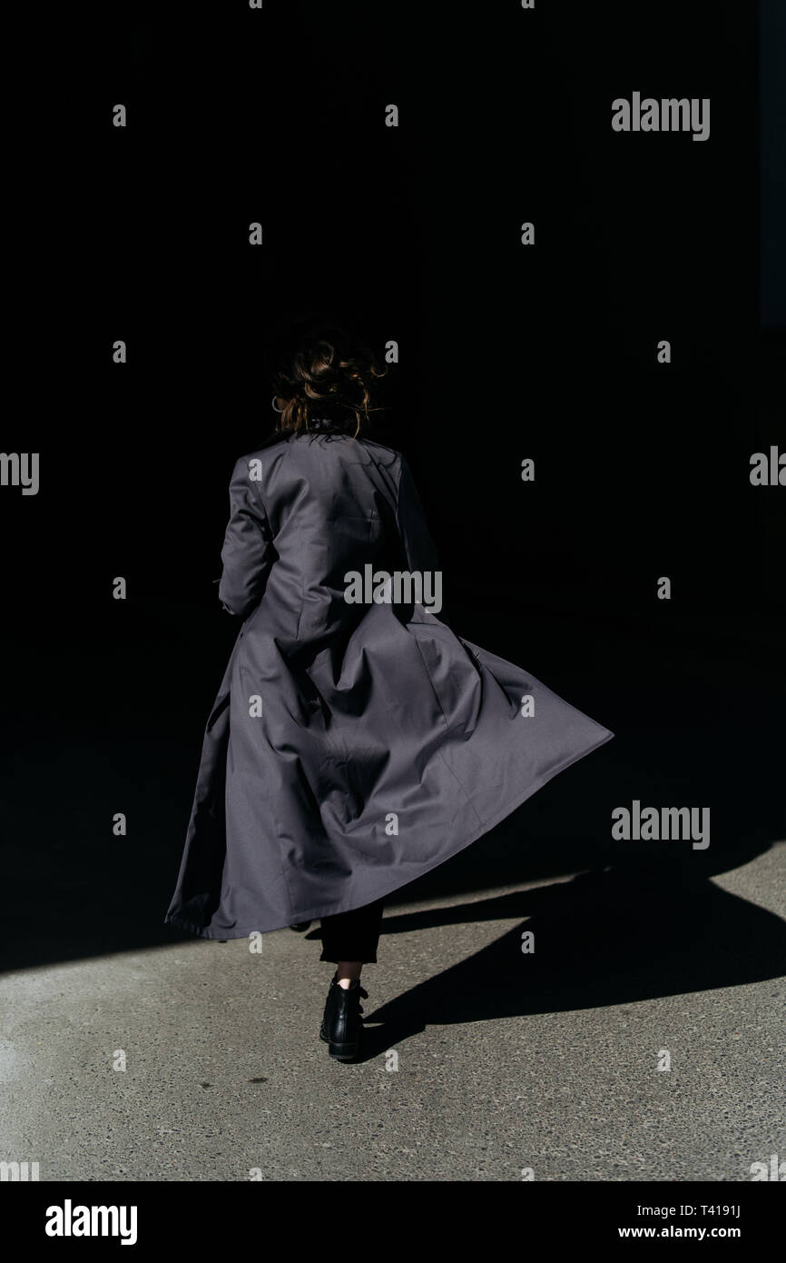 Rear view of a Woman walking away wearing a trench coat Stock Photo - Alamy