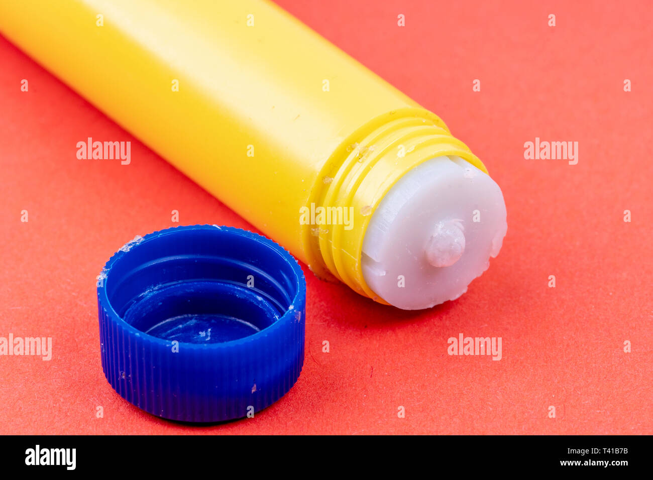 yellow glue stick with blue lid against red background Stock Photo Alamy