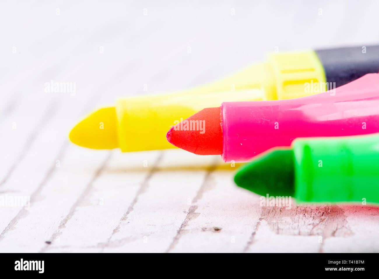 three colorful highlighters on white rustic wood Stock Photo