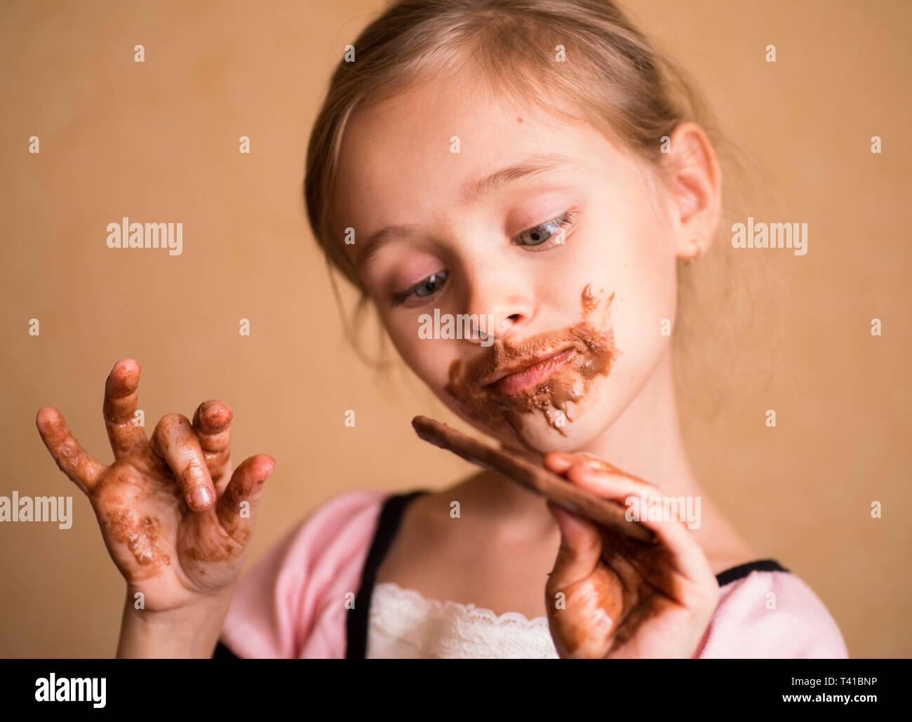 Girl with chocolate.Girls, children eat chocolate, a mouth and hands of girls are smeared with chocolate. Stock Photo