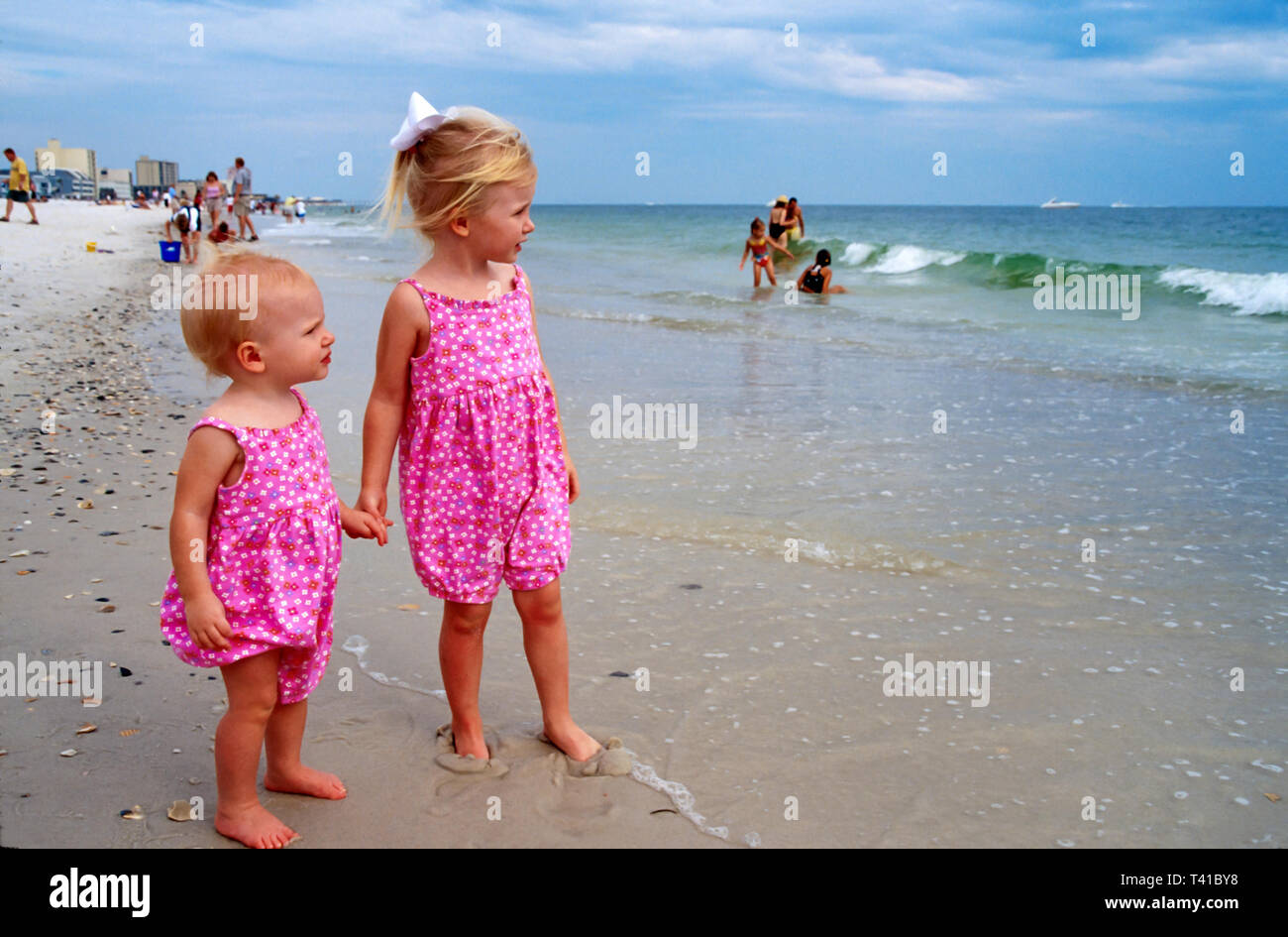 Alabama Gulf Coast Baldwin County Gulf Shores,surf Gulf of Mexico shore shoreline girls sisters holding hands,matching clothes, Stock Photo