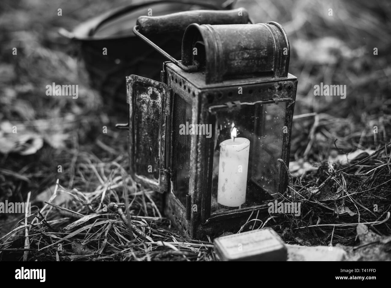 Old German Wehrmacht Times Of World War II Vintage Lantern With Burning Candle On Forest Ground. Photo In Black And White Colors. WWII WW2 Times. Stock Photo