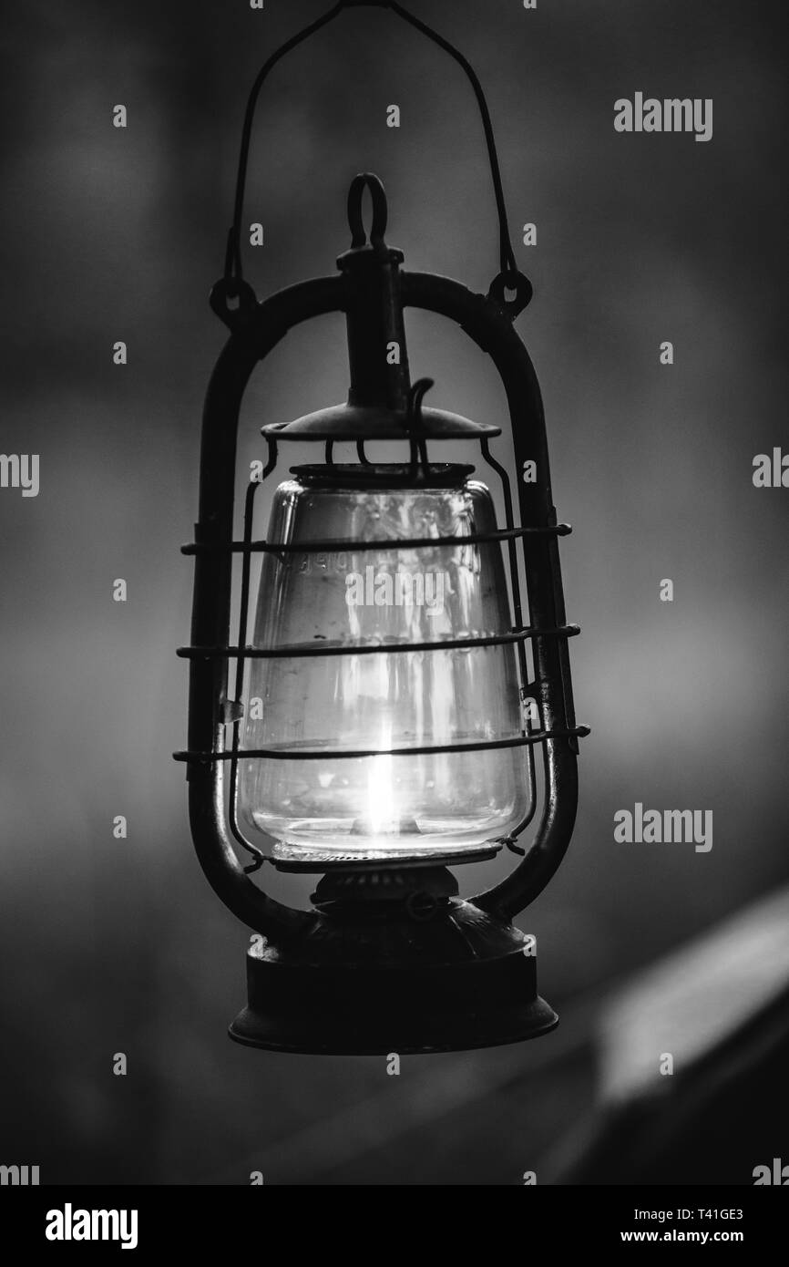 Old German Wehrmacht Times Of World War II Vintage Lantern With Burning Kerosene Wick Hanging On Camp In Summer Forest. Photo In Black And White Color Stock Photo