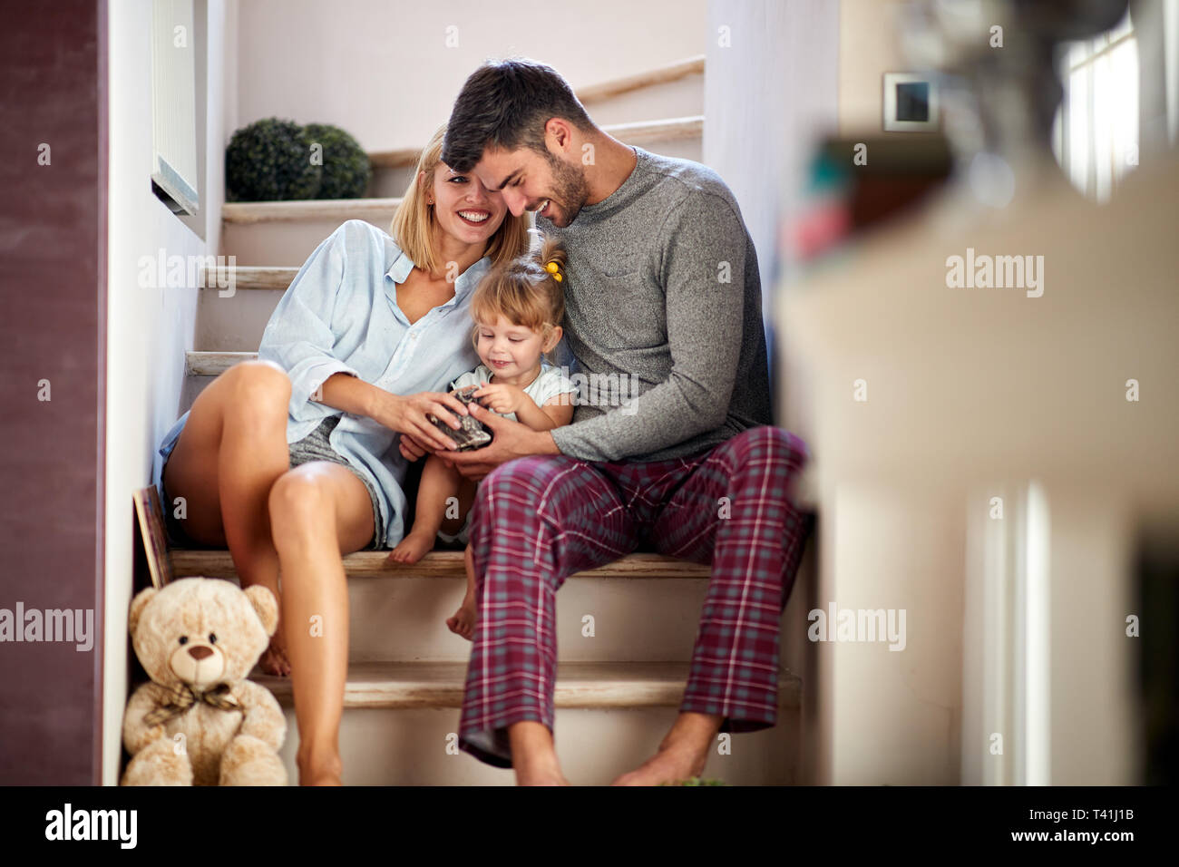 Mom and dad with adorable kid having fun on stairs Stock Photo - Alamy