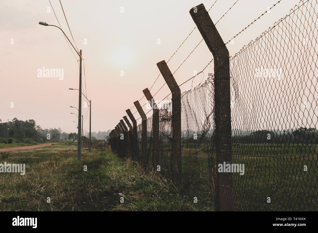 Perimeter fence, chain-link fencing showing the diamond patterning, with barbed wire protecting a property. Vintage toned Stock Photo