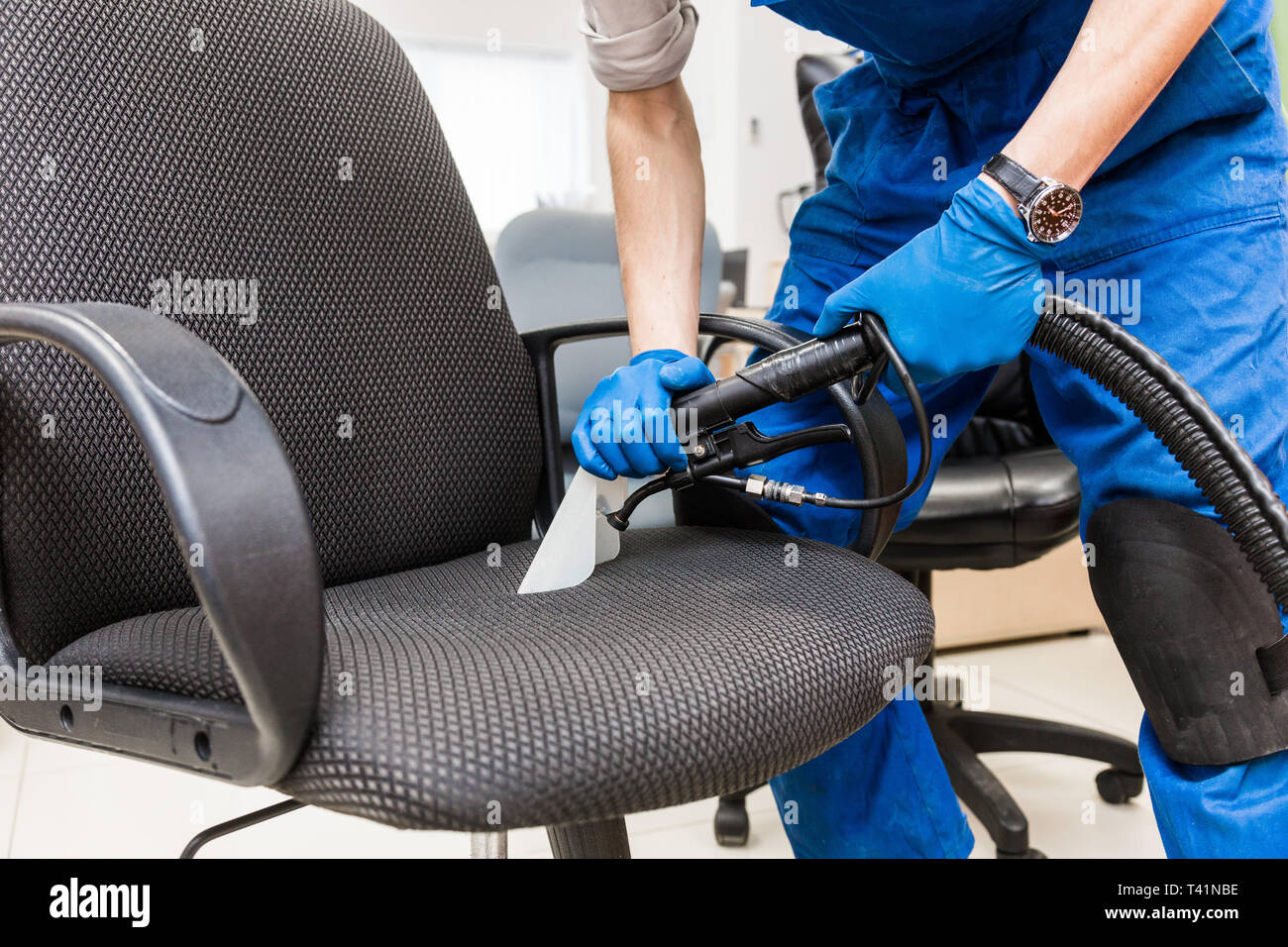 Cleaning service. Young man in workwear and rubber gloves cleans the ...