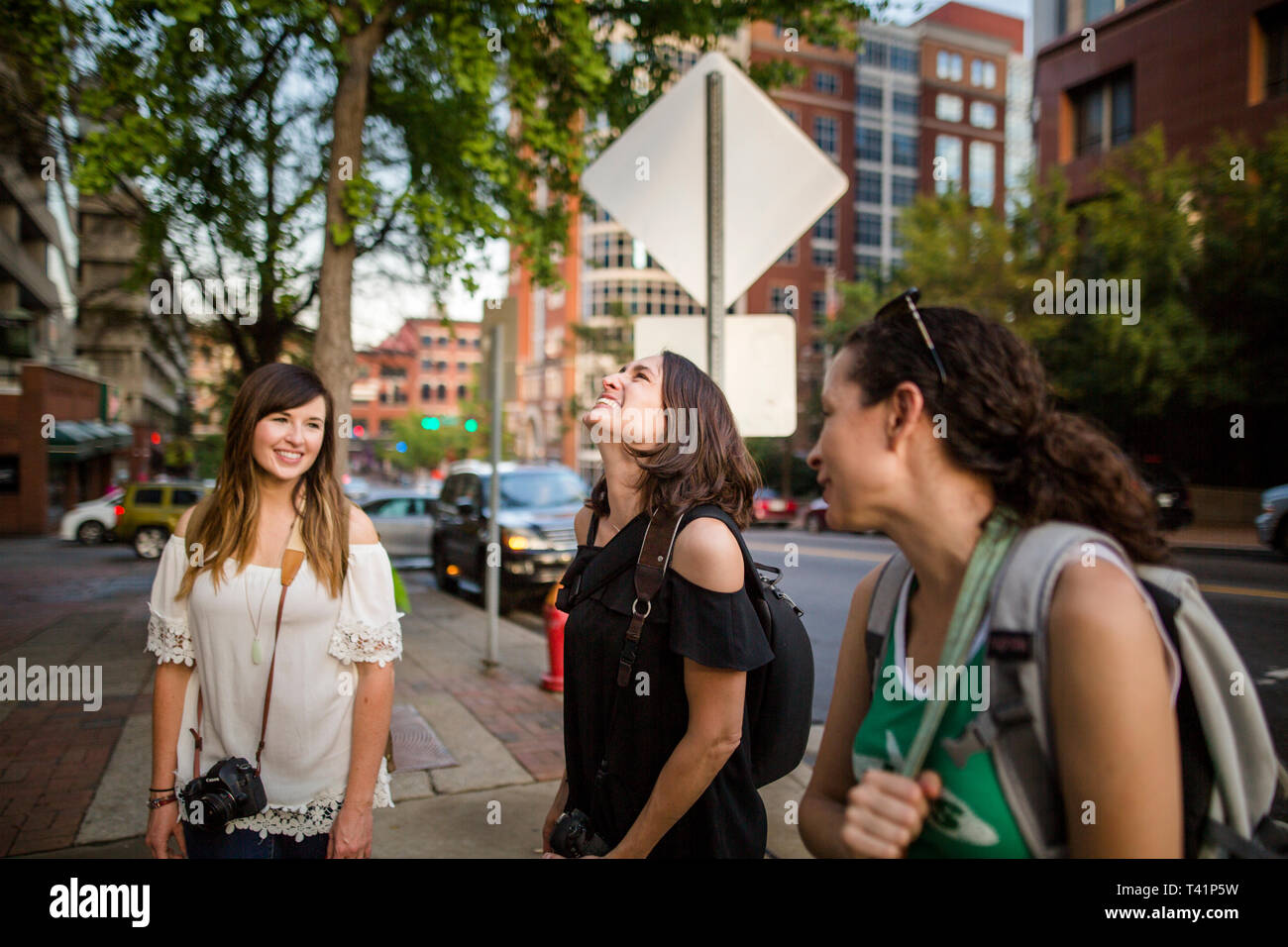 a group of laughing women tourists stand on a city street corner Stock Photo