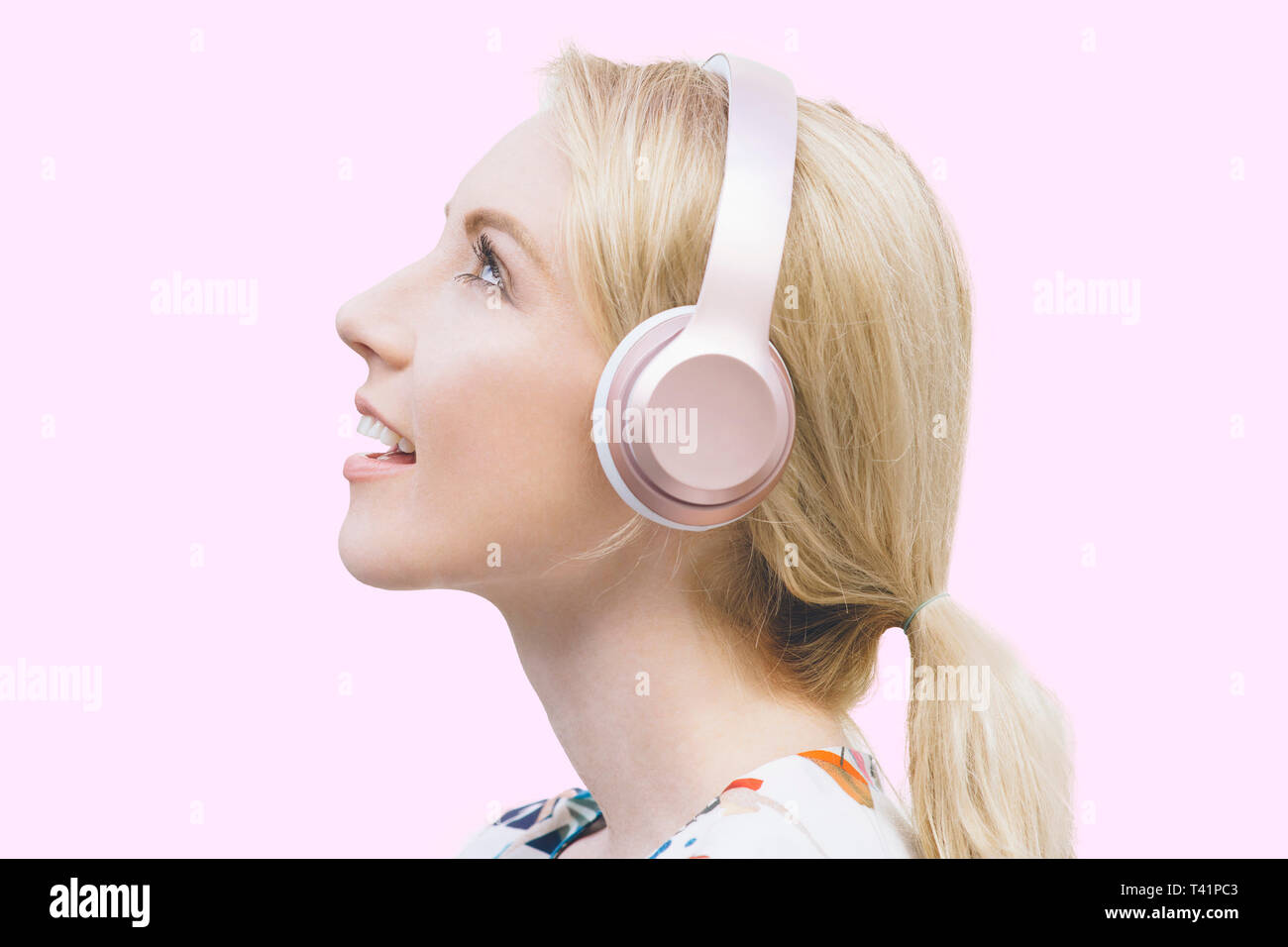 Female with blond hair listens to her headphones and is inspired Stock Photo