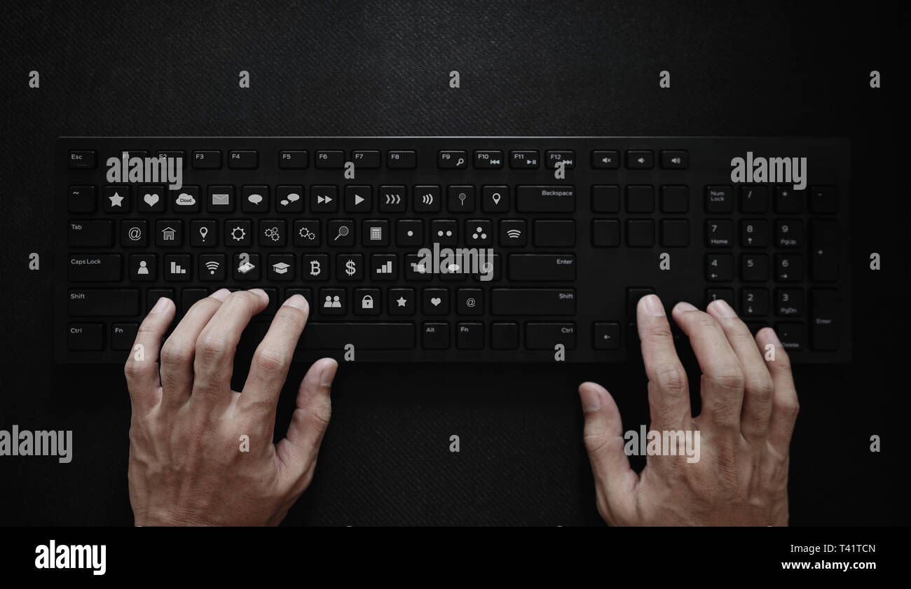 Hand typing on computer keyboard, with application icons on button. Application Programming Interface Stock Photo
