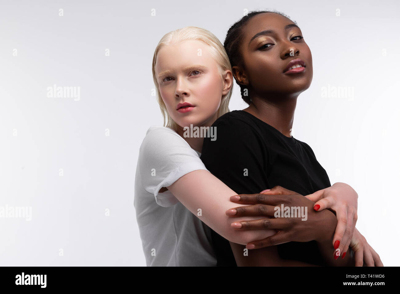 African-American friend. Blonde-haired woman wearing white t-shirt hugging  her African-American friend Stock Photo - Alamy