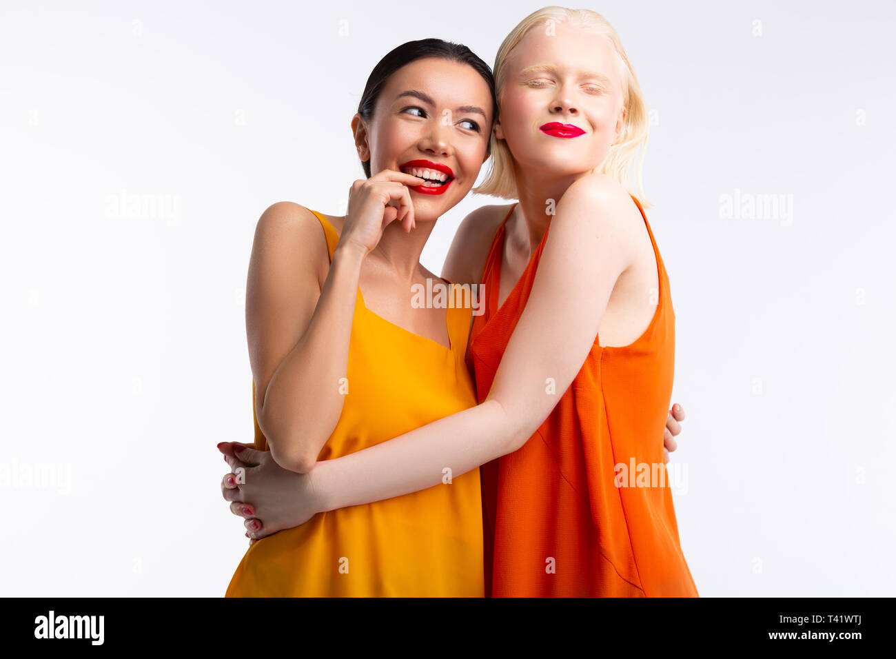 Women wearing bright dresses feeling truly happy together Stock Photo