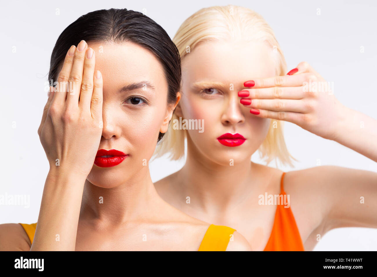 Models with bright red lips hiding part of their face while posing