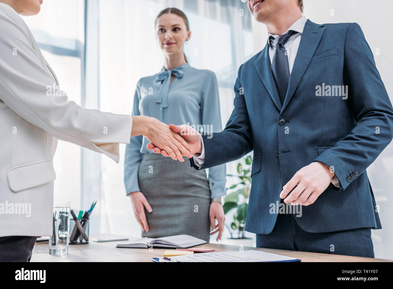 cropped view of cheerful recruiter shaking hands with woman near attractive colleague in office Stock Photo