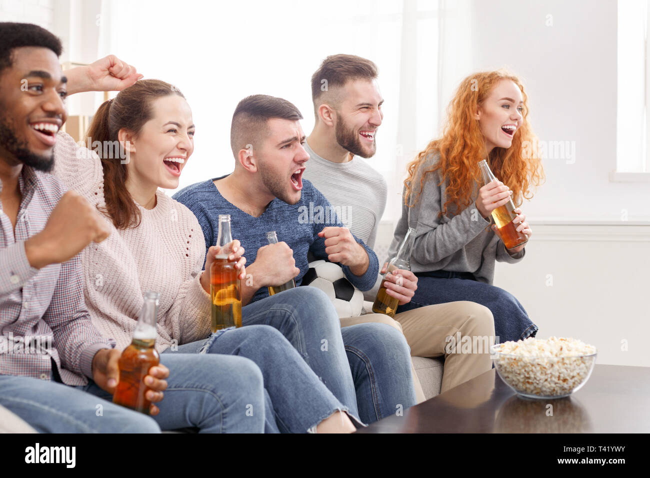 Cheering for favourite team. Friends watching match Stock Photo