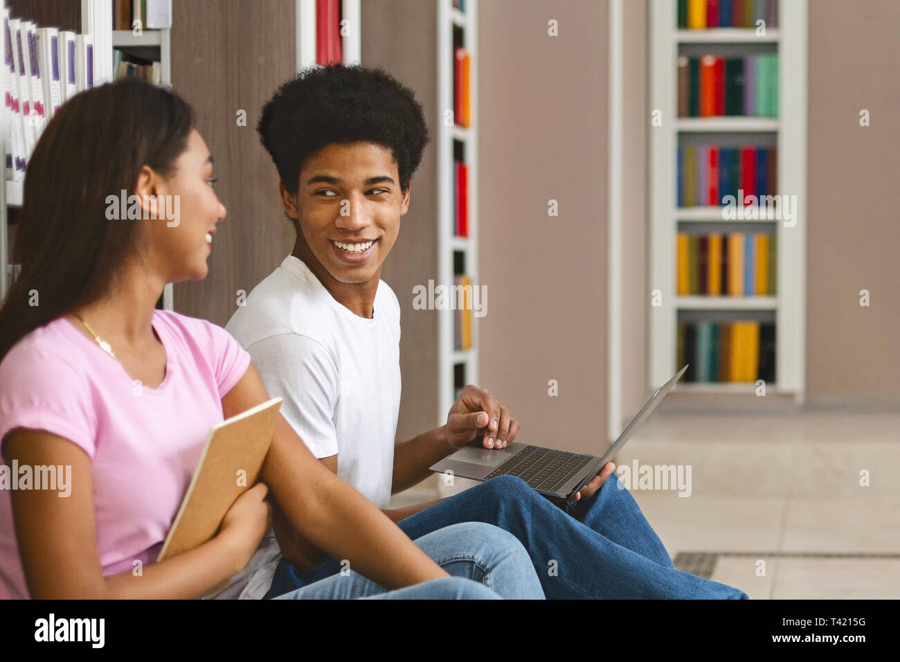 Couple of happy black students with laptop networking in library Stock Photo