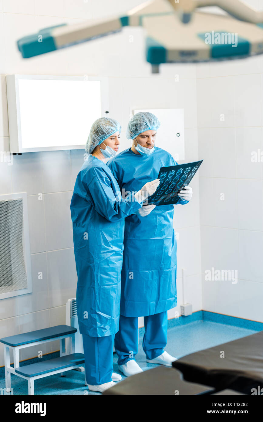 handsome and beautiful doctors in uniforms holding x-ray and talking in clinic Stock Photo
