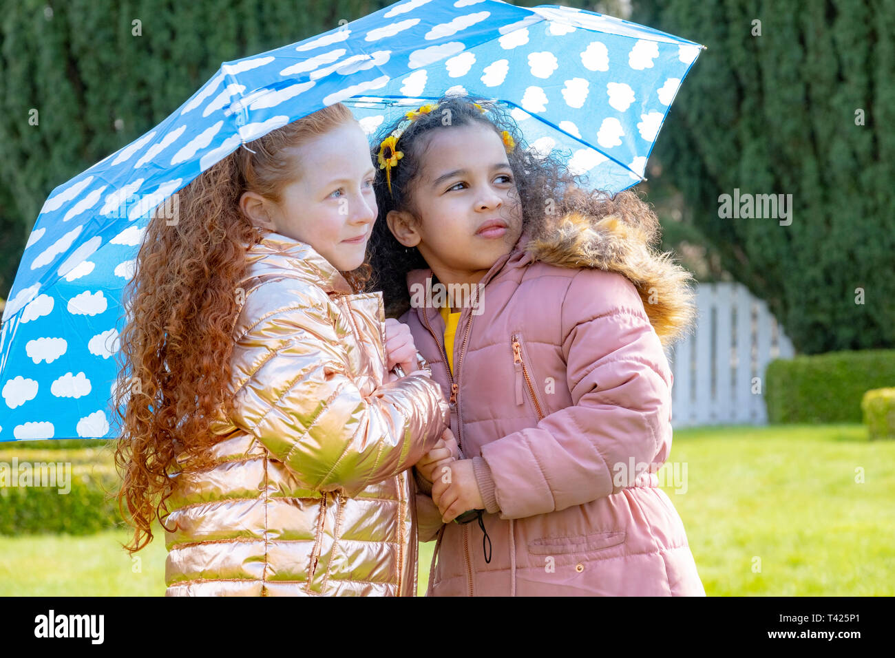 Children sheltering below an umbrella Stock Photo
