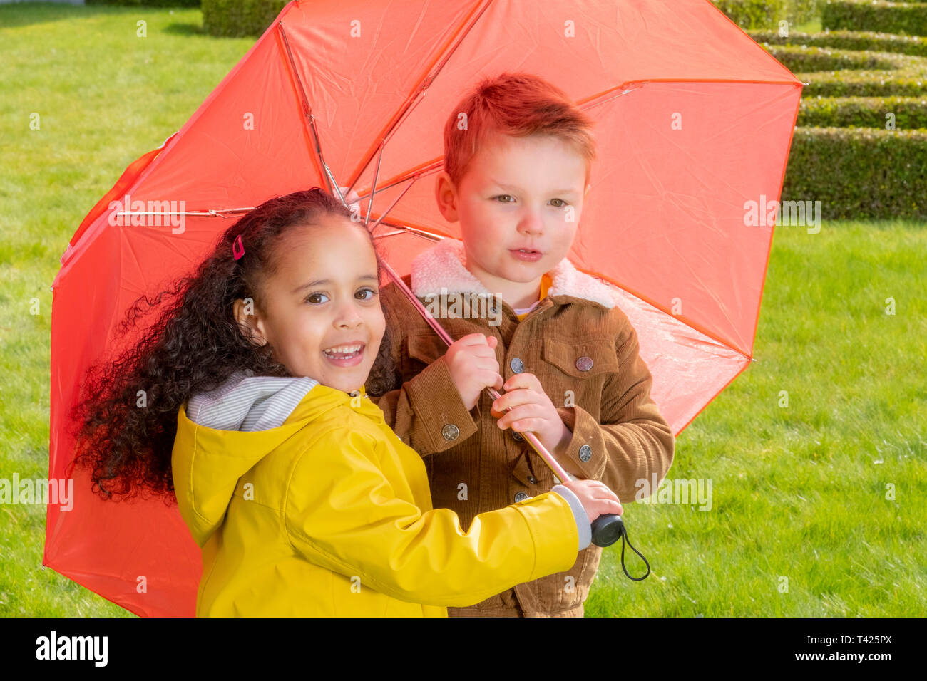 Children sheltering below an umbrella Stock Photo