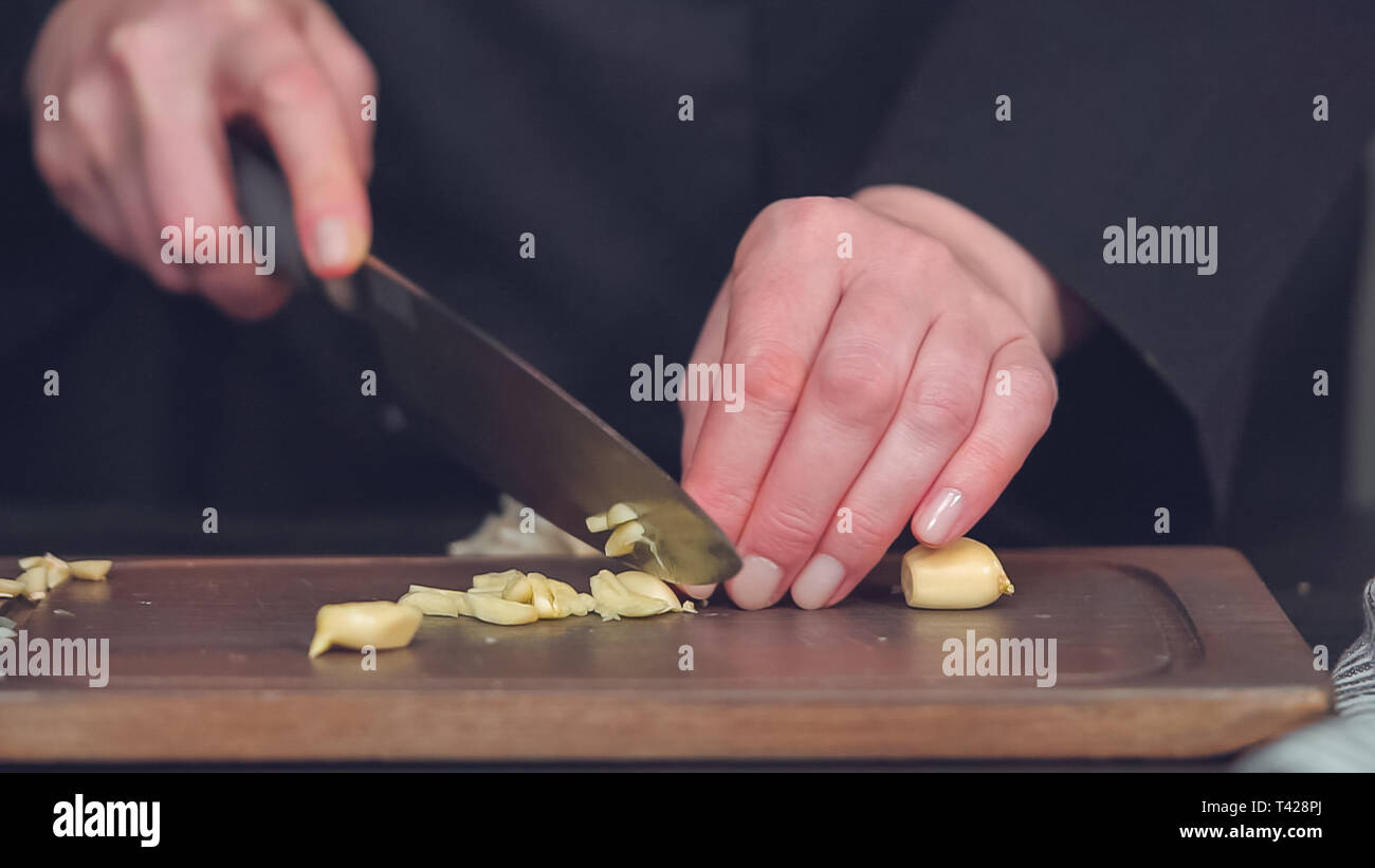 Step by step. Dicing organic garlic on wood cutting board Stock Photo