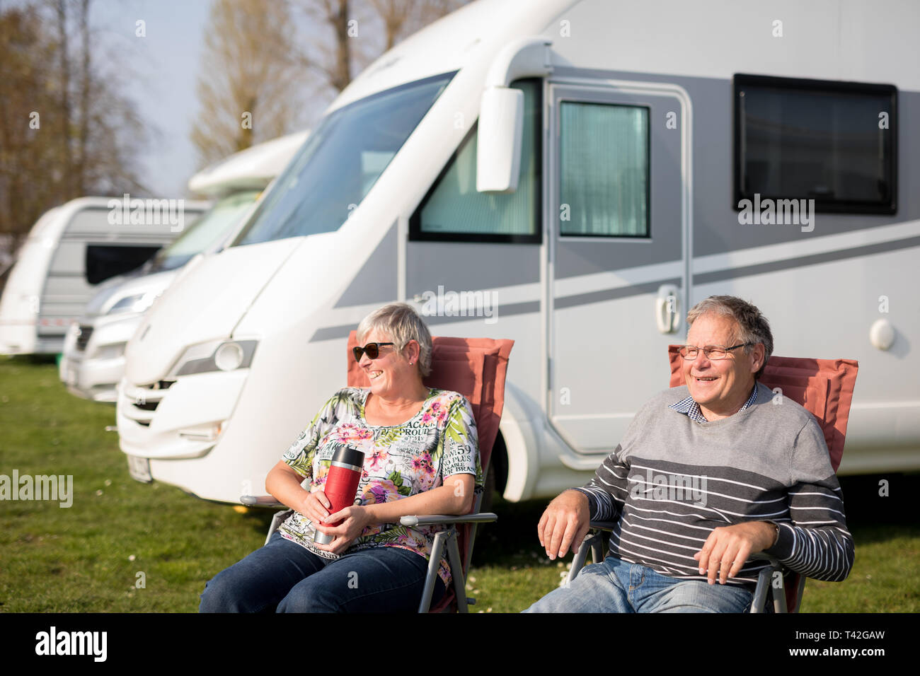 06 April 2019, Lower Saxony, Rinteln: The campers Moni and Gerd Siedentopf enjoy the sunny weather in front of their caravan on the camping site at Doktorsee in the Weserbergland. Many campsite providers may still rave about the past season today. They now hope that visitors will remember the long warm summer and book again. Photo: Moritz Frankenberg/dpa Stock Photo