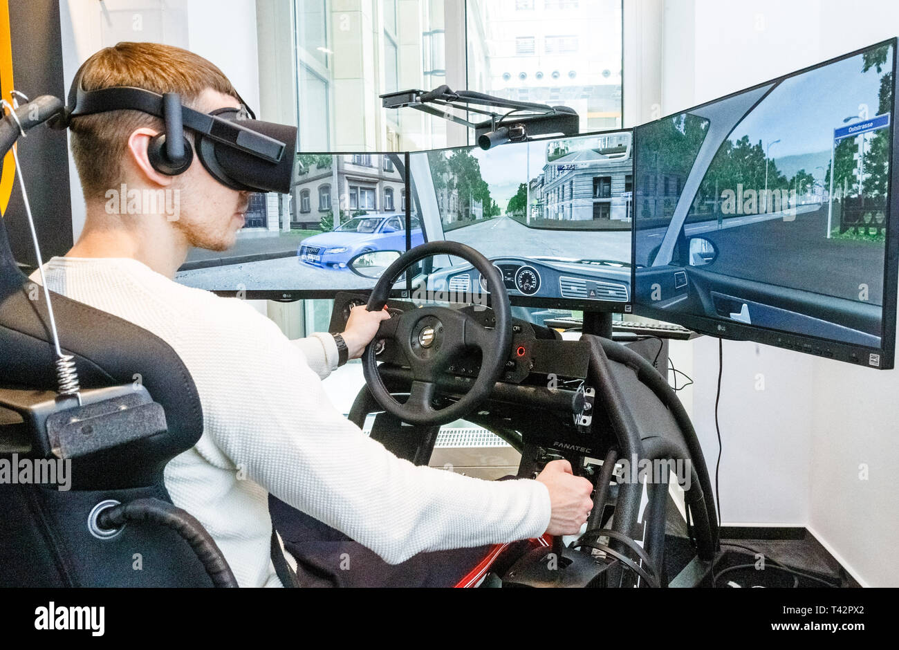 Hamburg, Germany. 13th Apr, 2019. A young man sits with VR (Virtual Reality) glasses in 360 degree driving simulator. By practicing in artificial reality, driving lessons are to be saved in