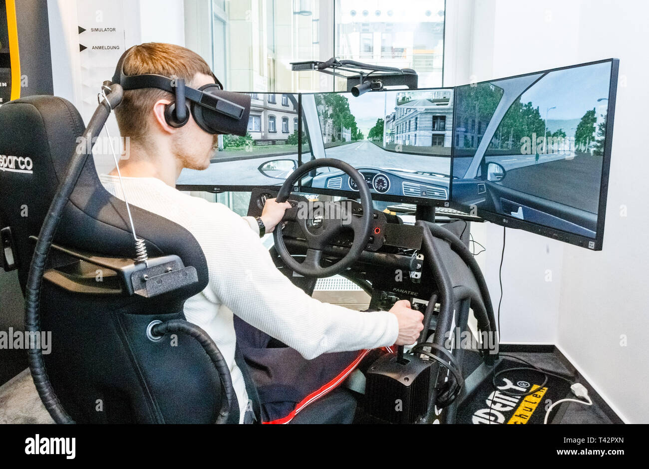 Hamburg, Germany. 13th Apr, 2019. A young man sits with VR (Virtual Reality) glasses in 360 degree driving simulator. By practicing in artificial reality, driving lessons are to be saved in