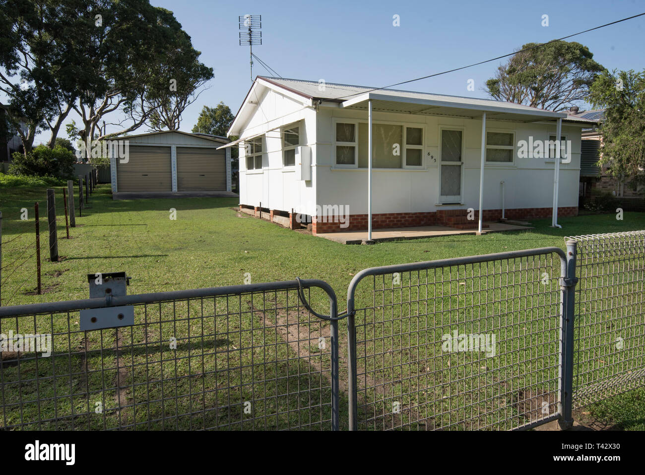A small 1950's fibro (Asbestos fibrous cement) home with a double garage and galvanized iron front fence in the NSW south coast village of Kioloa Stock Photo