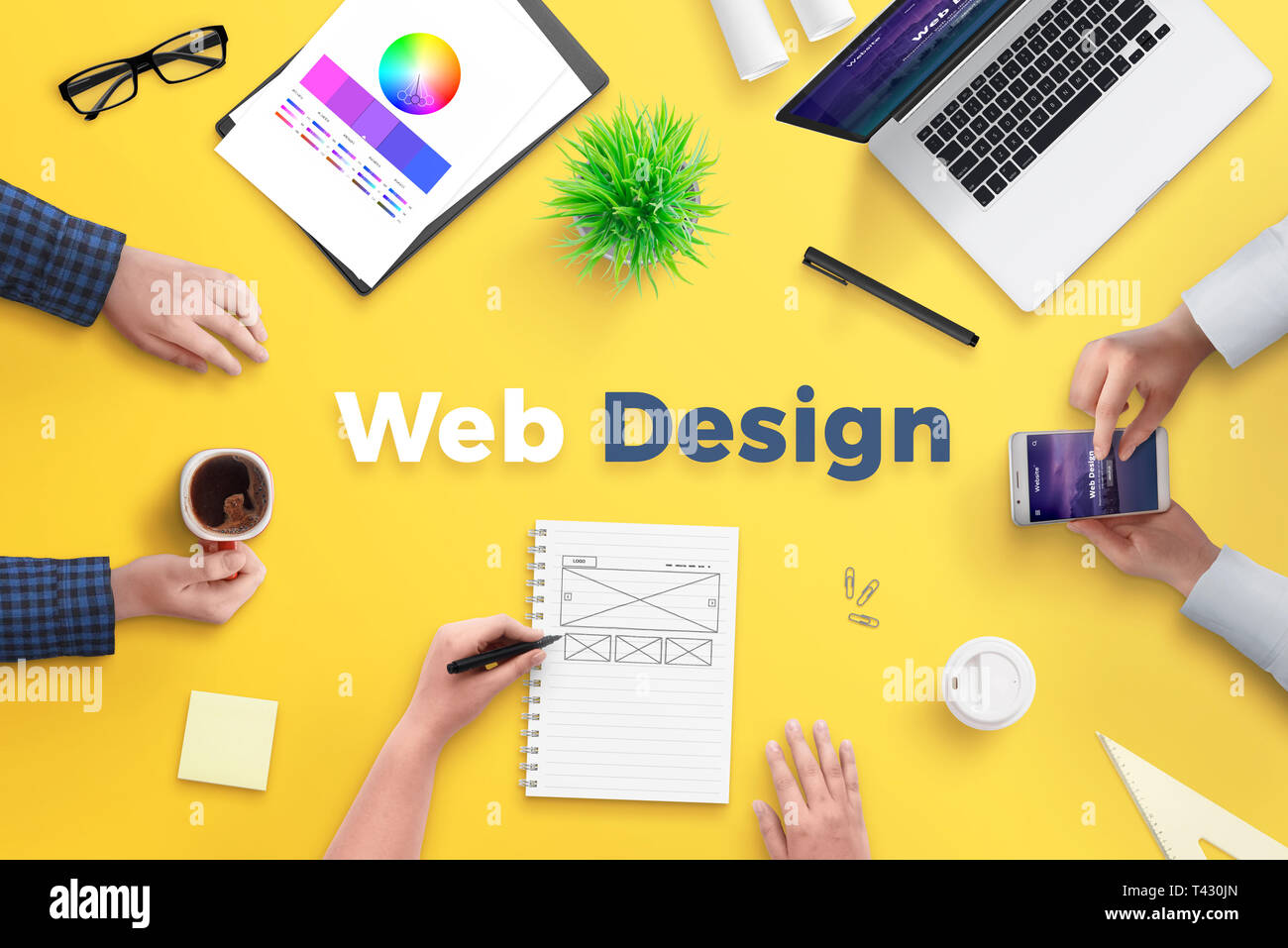 Web design team work on project concept. Yellow desk with web design text. Top view, flat lay. Stock Photo