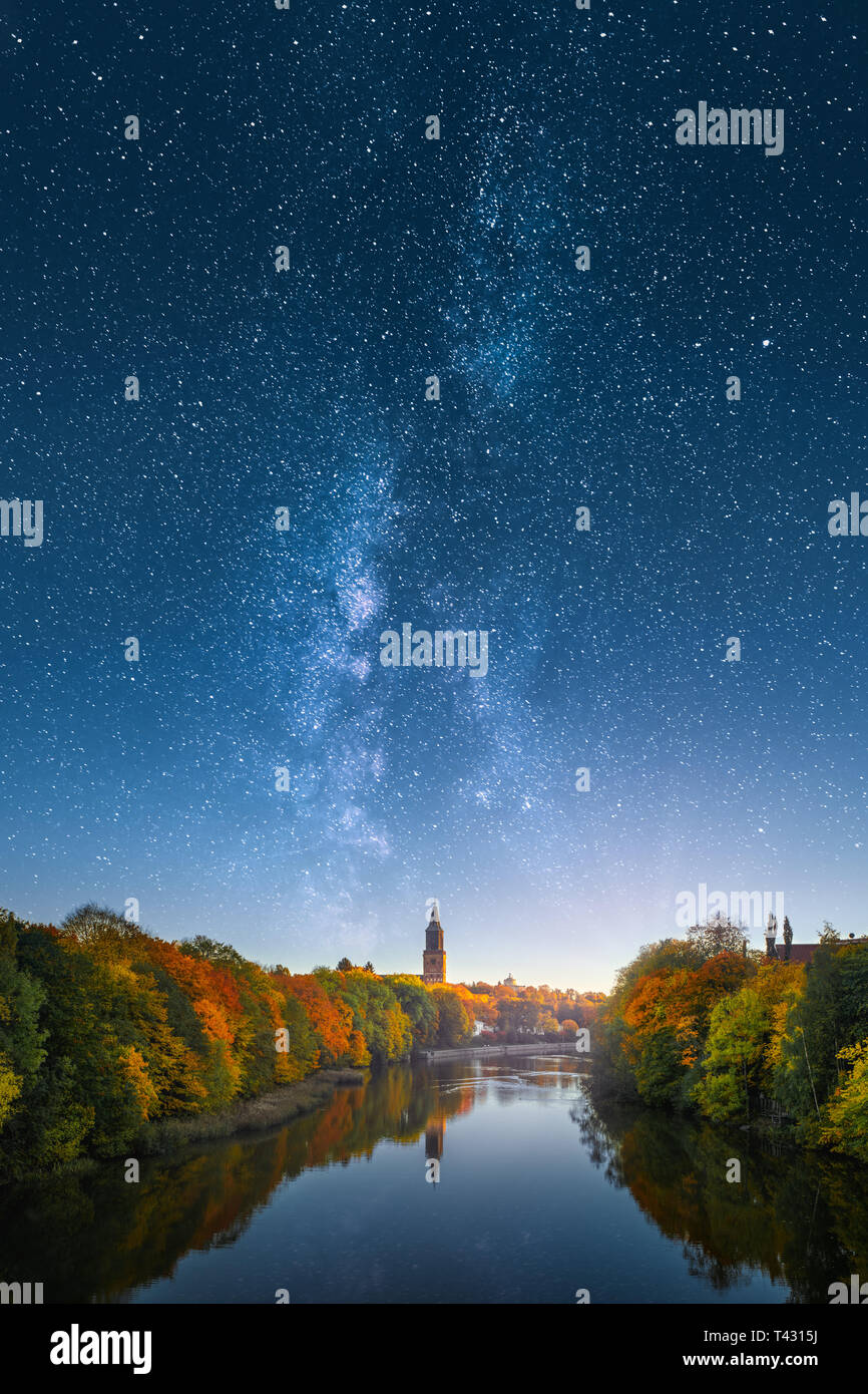 Ethereal image of fall foliage and Aura river with Turku Cathedral in Finland against beautiful milky way on the sky. Stock Photo