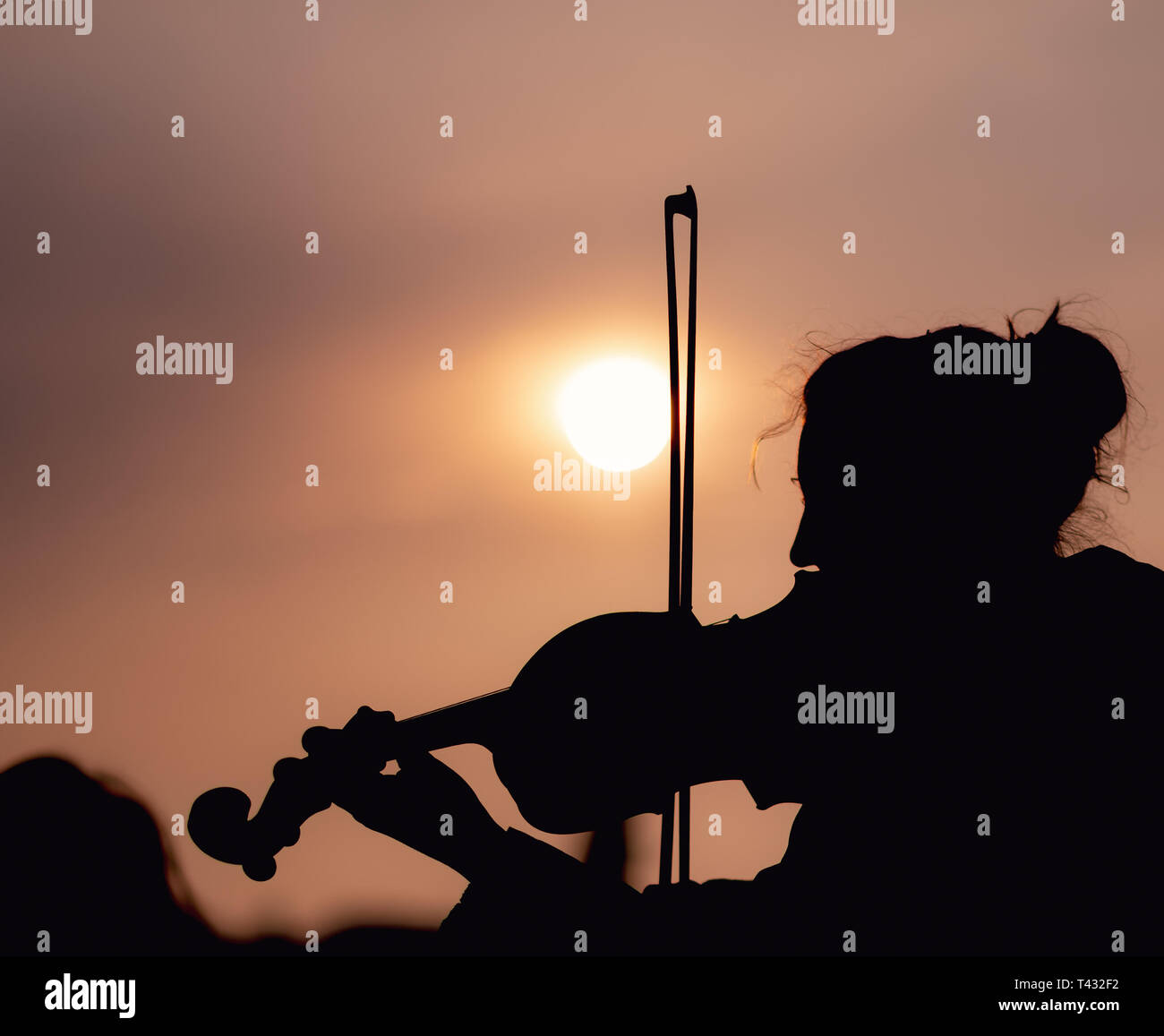 Silhouette of female playing the violin during sunset against the sun - Taken in Prague Stock Photo