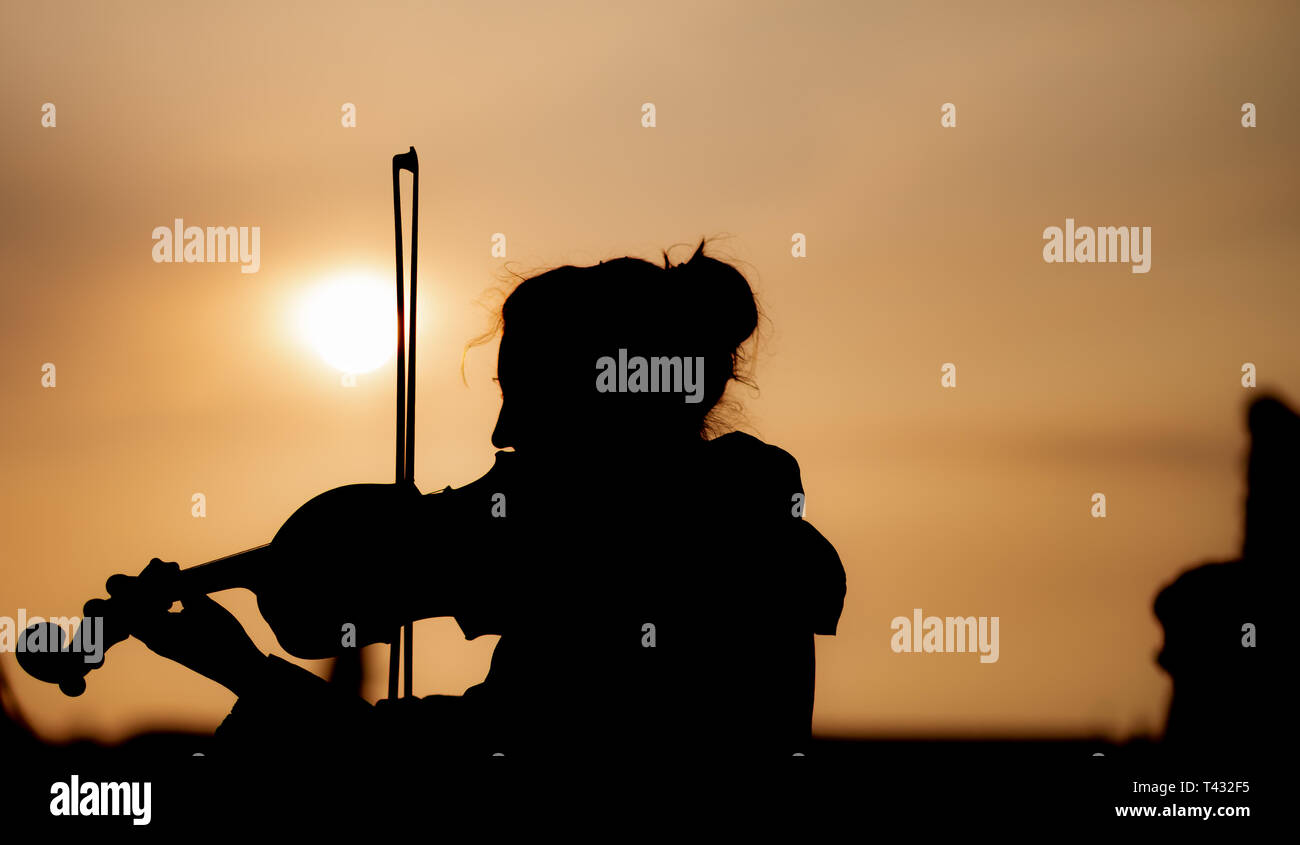 Silhouette of female playing the violin during sunset against the sun - Taken in Prague Stock Photo