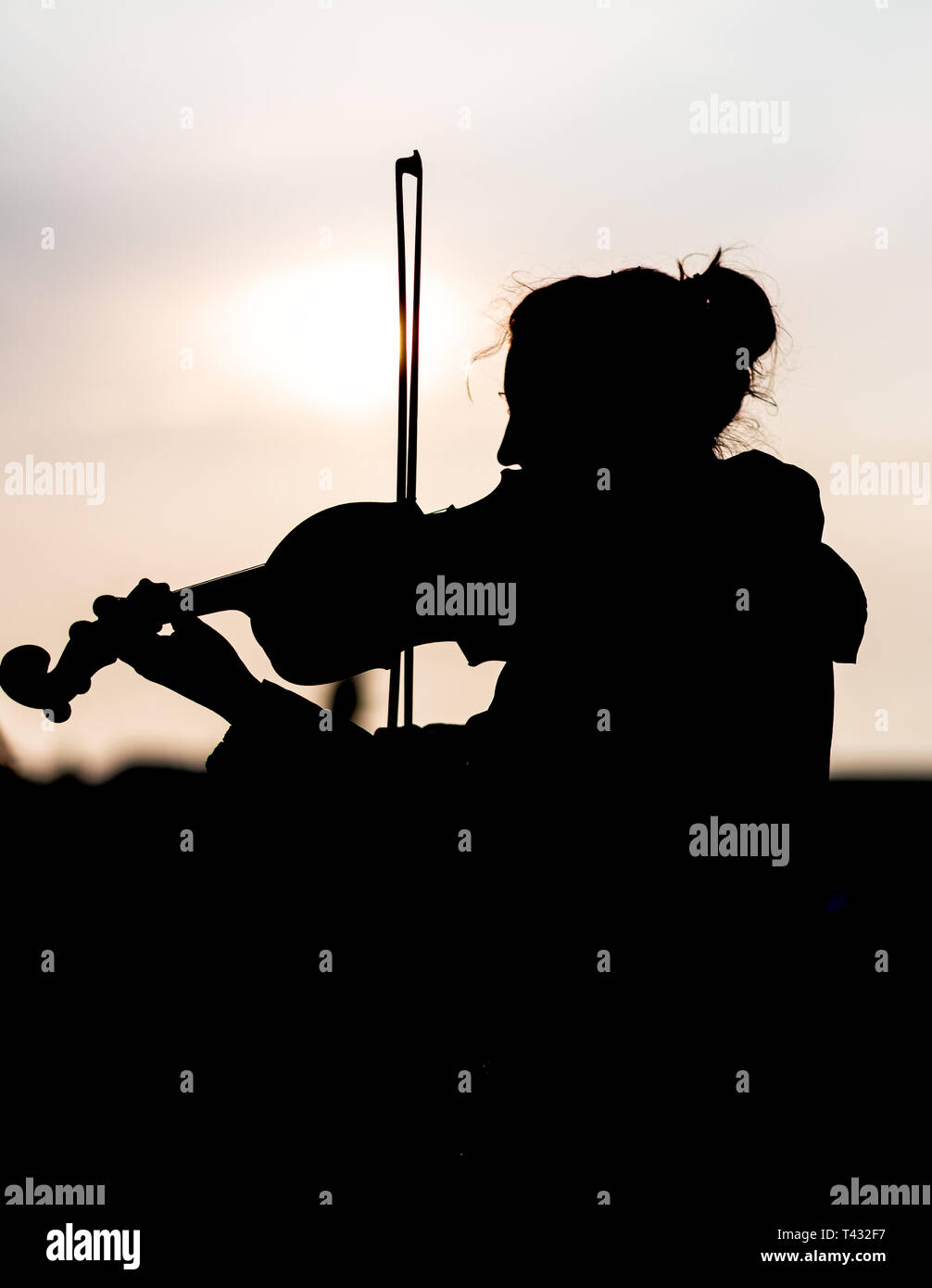 Silhouette of female playing the violin during sunset against the sun - Taken in Prague Stock Photo
