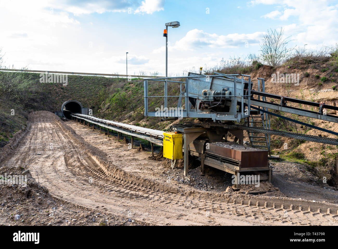 A string of transport belting in a  gravel pit for transporting gravel and sand over long distances, the belts go under of the road. Stock Photo
