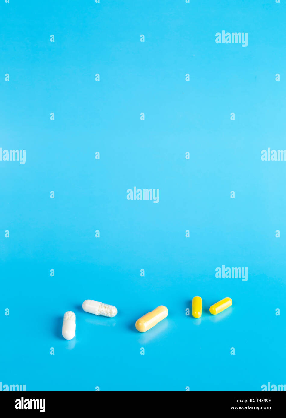 White and yellow medical capsules on a blue background Stock Photo Alamy