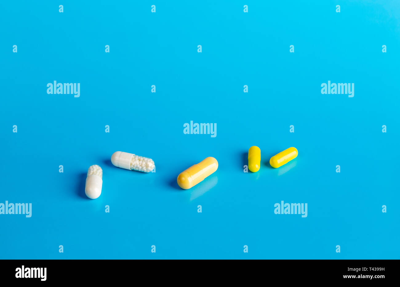 White and yellow medical capsules on a blue background Stock Photo Alamy
