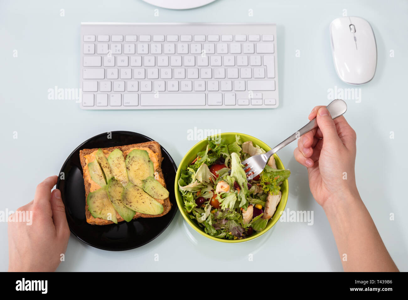 An Overhead View Of Businessperson's Hand Eating Salad With Fork On