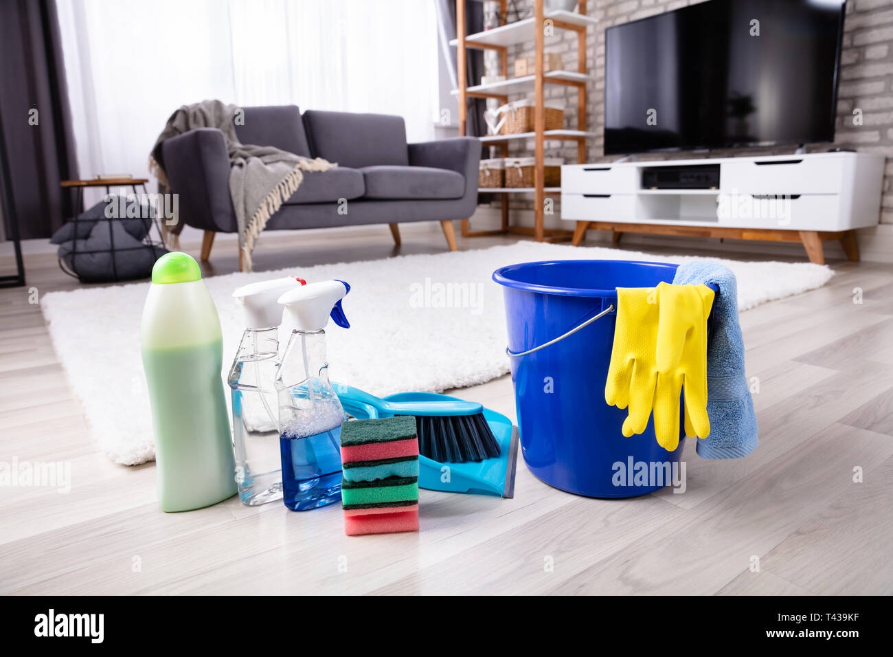 Close-up Of Cleaning Products And Tools On Hardwood Floor In Living Room Stock Photo