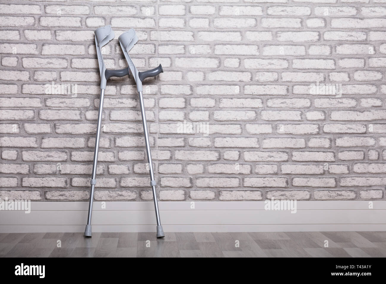 Pair Of Crutches Leaning Against Brick Wall Stock Photo