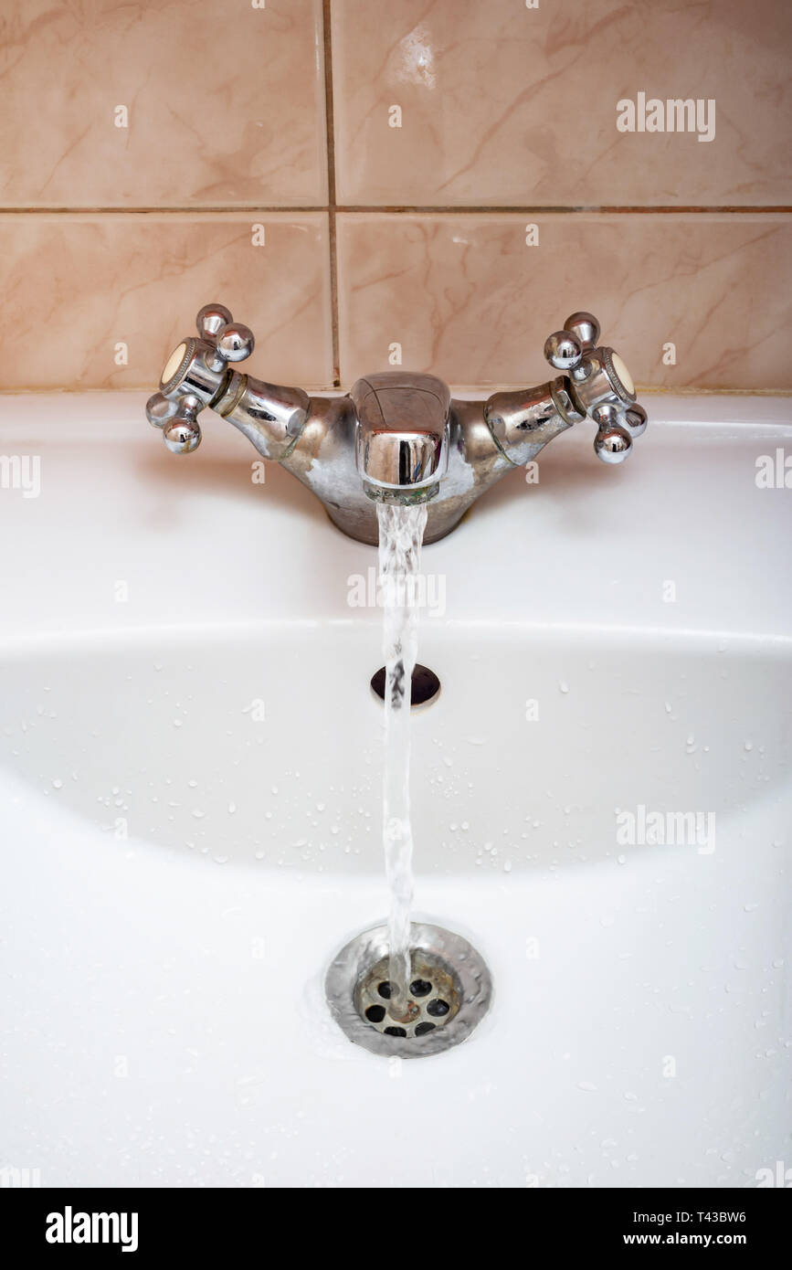 Vertical image of a tap with water flowing strongly under high pressure Stock Photo