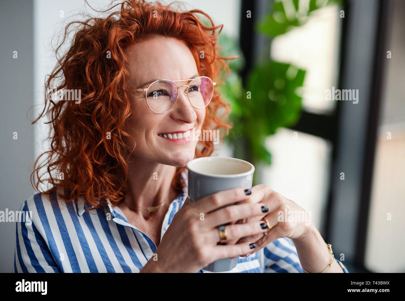 A portrait of businesswoman in an office, holding a cup of coffee. Stock Photo