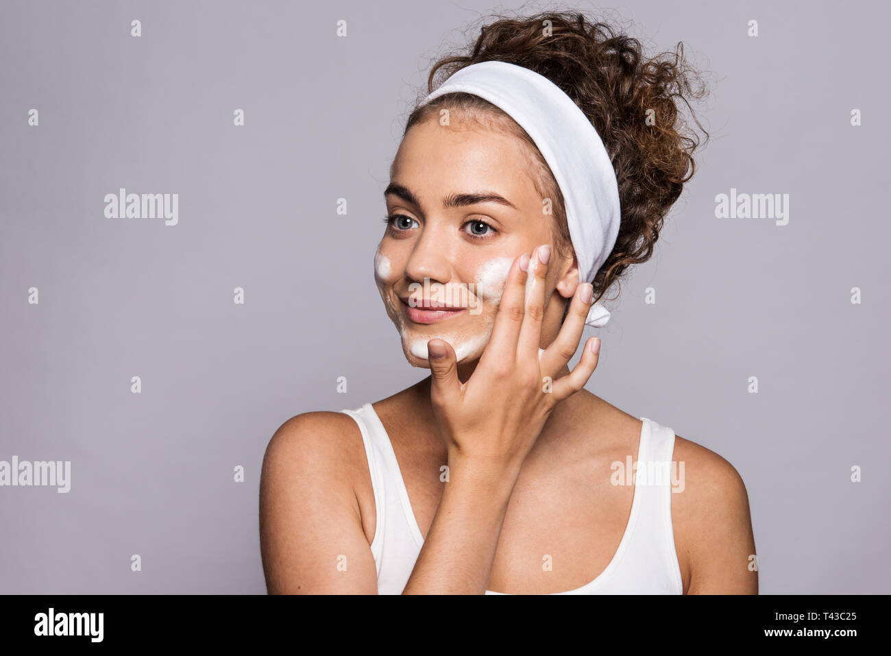 Portrait of a young woman cleaning face in a studio, beauty and skin care. Stock Photo
