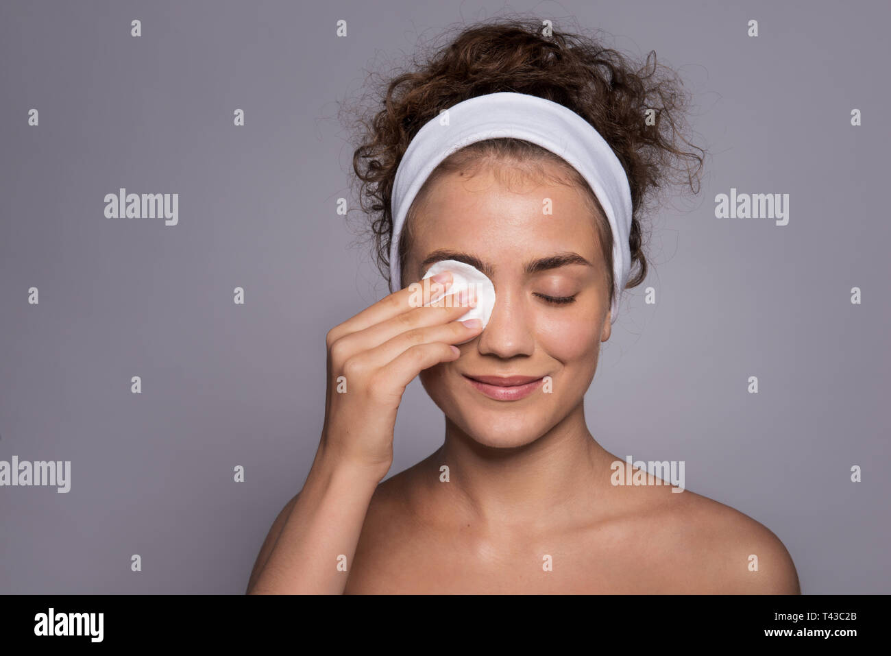 A portrait of a young woman cleaning face in a studio, beauty and skin care. Stock Photo
