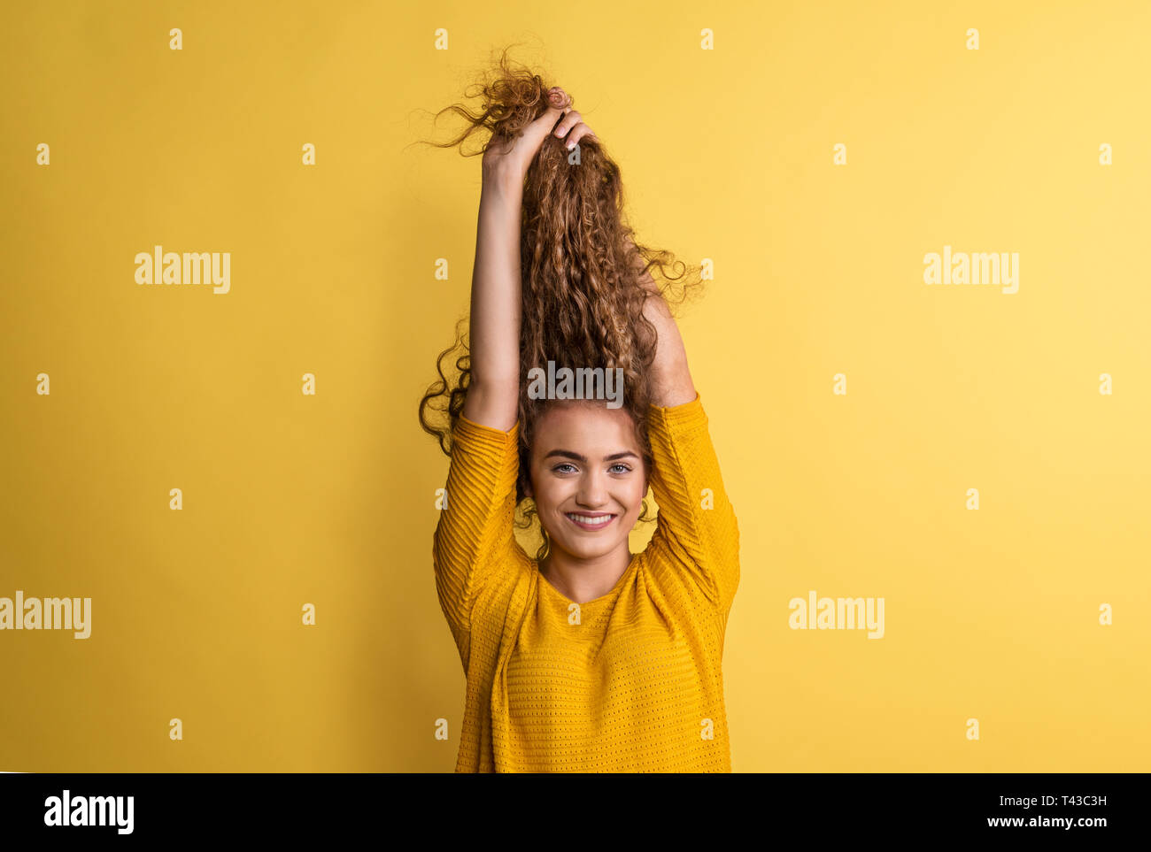 Portrait of a young woman in a studio on a yellow background, having fun. Stock Photo