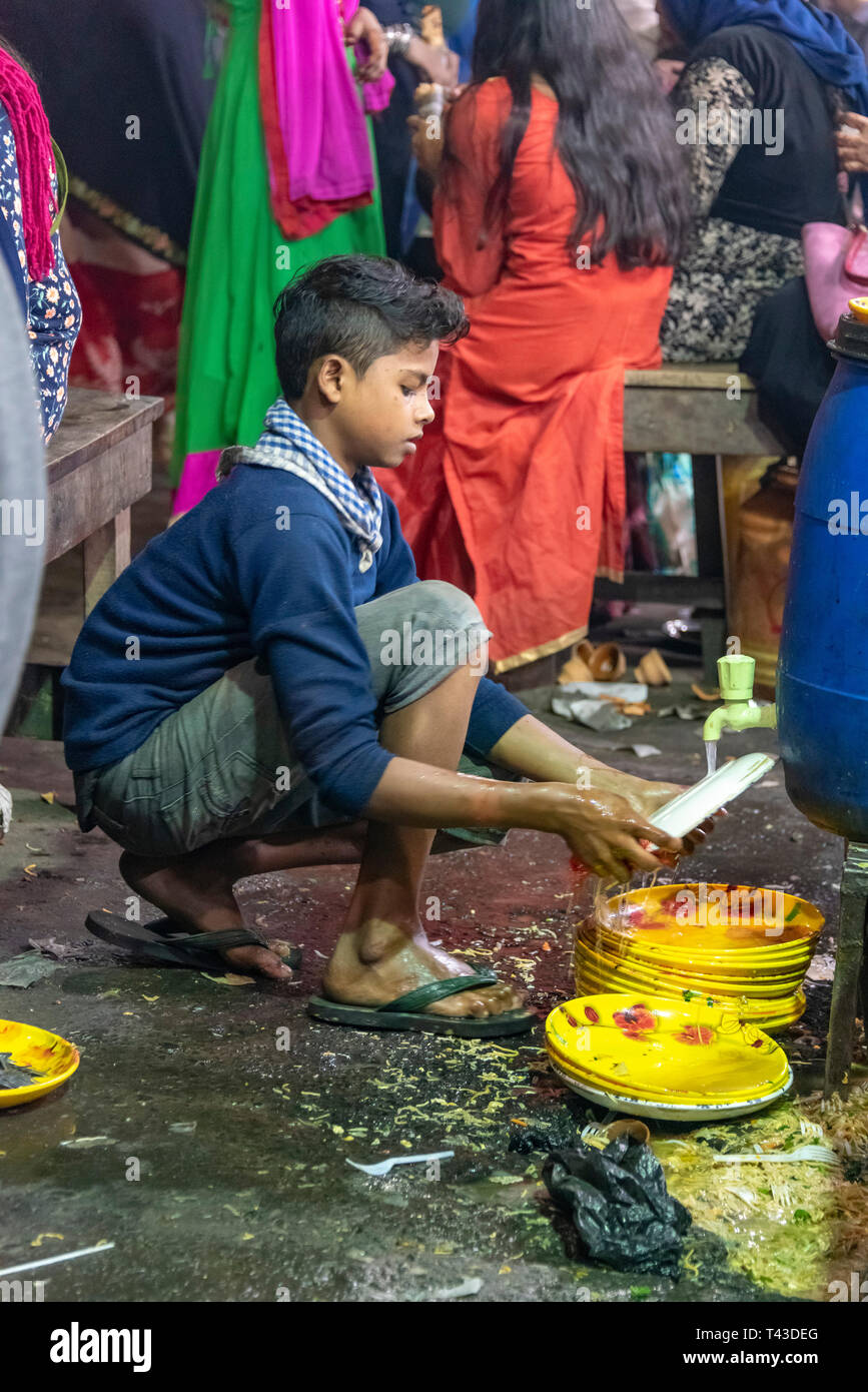 Vertical view of a young boy washing plates in the streets of Kolkata aka Calcutta, India. Stock Photo