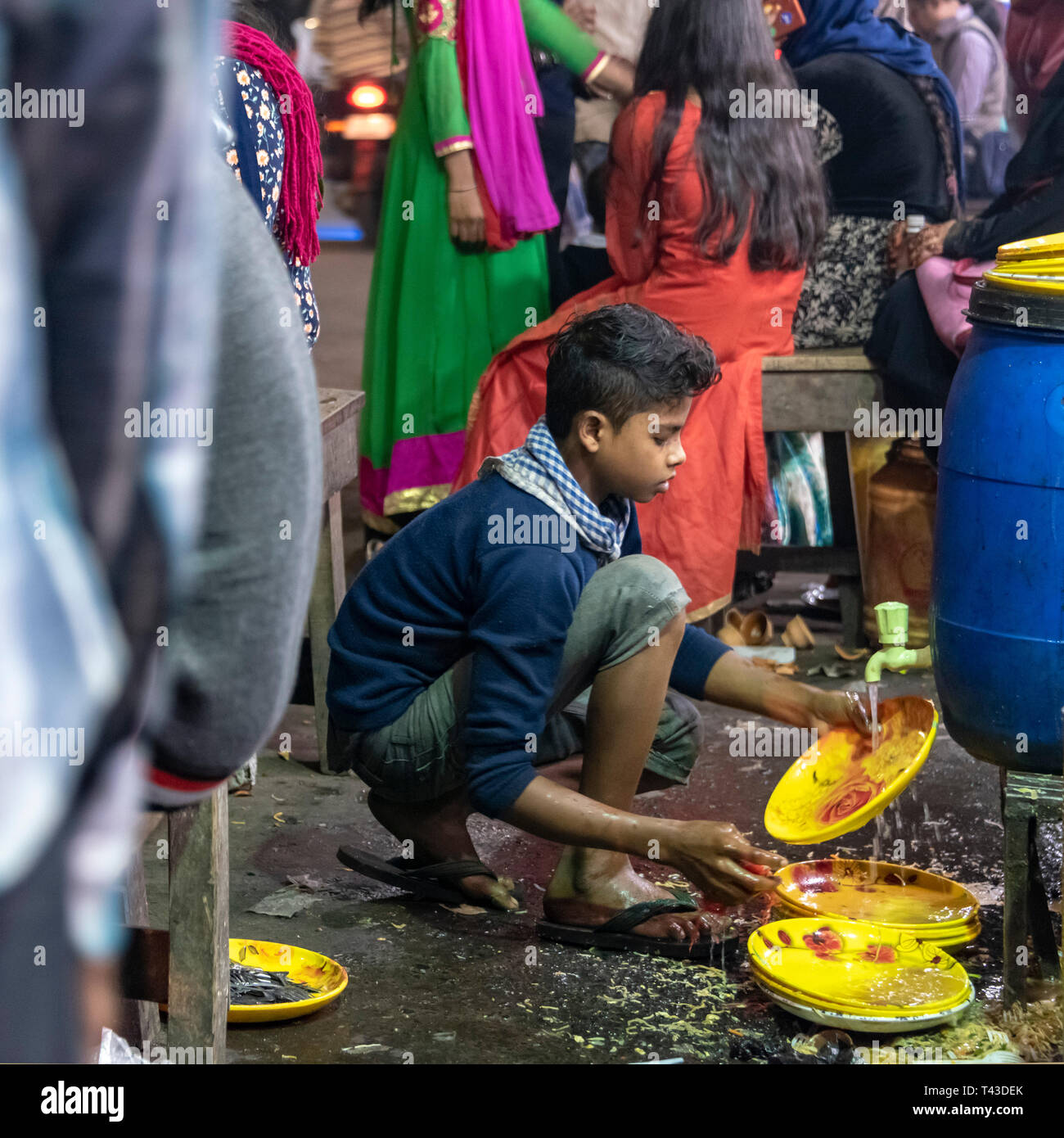 Square view of a young boy washing plates in the streets of Kolkata aka Calcutta, India. Stock Photo